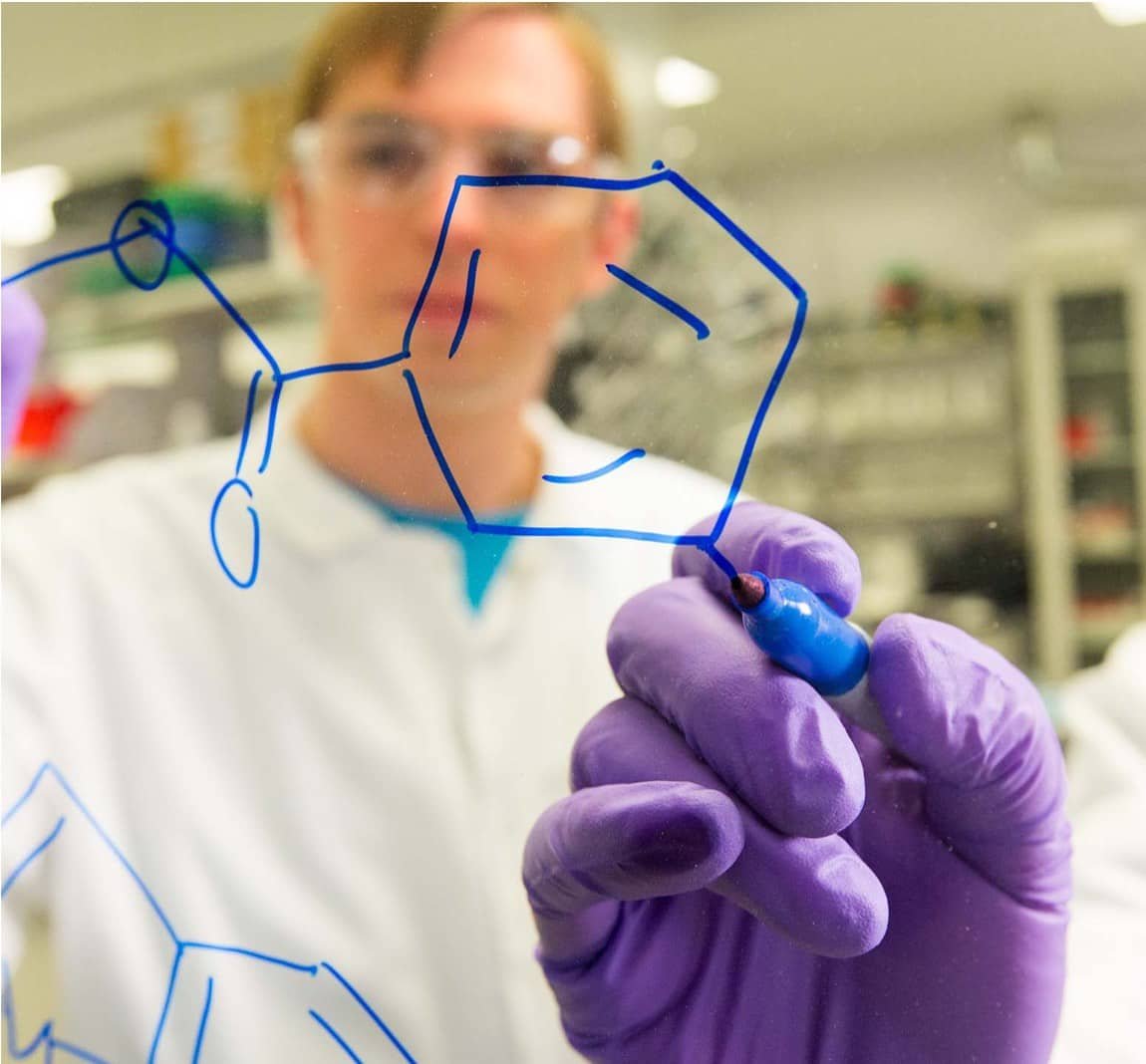 Scientists drawing molecules on a white board